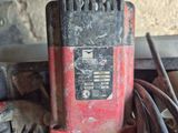 une perceuse électrique rouge et noire posée sur une pile d'outils