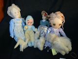 five dolls sitting next to each other on a black cloth