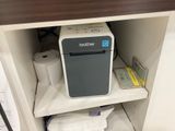a small printer sitting on a shelf in the corner of a cabinet