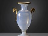 un vase en verre muni d'une poignée dorée, posé sur une table