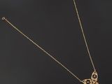 a gold necklace with a butterfly pendant on a black background