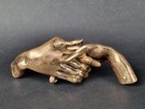 une image représentant une statue en bronze d'une main tenant une autre main