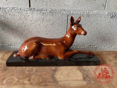 statue d'un cerf couché sur un socle en bois