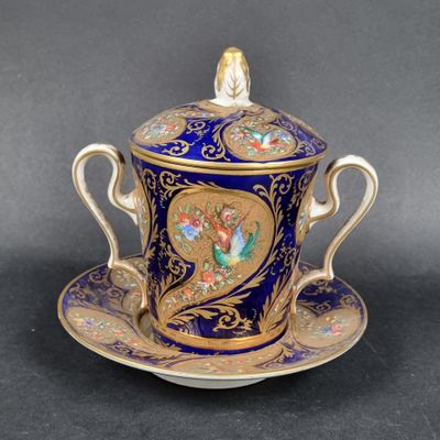 une tasse et une soucoupe bleues et dorées ornées d'un oiseau