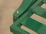 a close up of a green bench with a metal arm rest