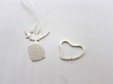 a close up of a necklace with a heart and a bird on it