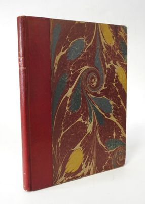 an old book with a red cover sitting on top of a white table