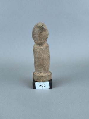 une petite statue en pierre représentant une personne, posée sur un socle