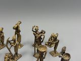 brass figurines of people with instruments and instruments on a white surface