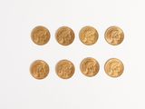 several gold coins are arranged in a row on a white surface