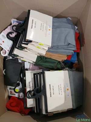 une boîte remplie de vêtements, avec une paire de ciseaux à l'intérieur