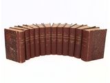 six old books lined up in a row on a white surface