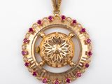 a close up of a gold pendant with pink stones on a white background
