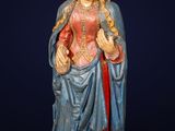 une statue représentant une femme en robe bleue avec un ruban rouge