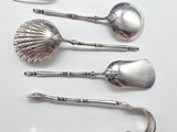 five silver spoons and a fork on a white surface