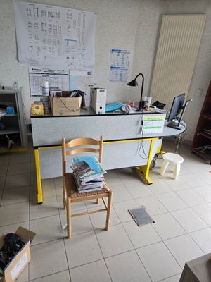 un bureau avec une chaise, dans une pièce où se trouvent de nombreuses boîtes