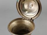 an antique silver vase with a lid open on a gray background