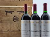 trois bouteilles de vin rouge sont posées devant une caisse en bois