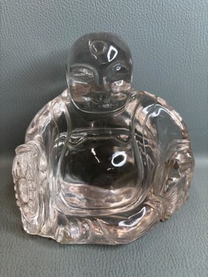 une figurine de Bouddha en verre posée sur une table