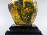 a close up of a yellow and black stone sculpture on a black base