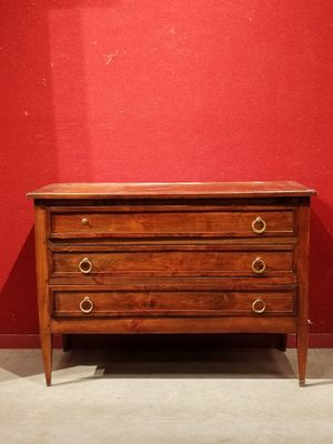 une commode en bois dans une pièce aux murs rouges