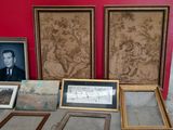 many framed pictures on a table with a red wall in the background