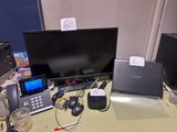 a desk with a laptop, monitor, phone, and other electronics on it