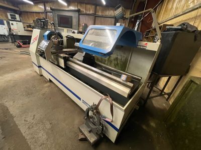 Une grande machine est posée dans un entrepôt, avec d'autres machines en arrière-plan.
