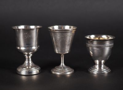 trois gobelets en argent posés les uns à côté des autres sur une surface noire
