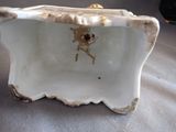 a white porcelain box with a gold handle on a table