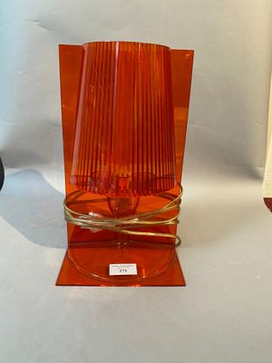 an orange glass vase with a gold base on a white background