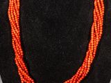 an orange beaded necklace on a black mannequin