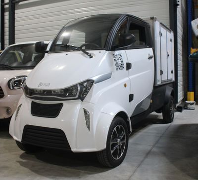 une petite voiture blanche garée dans un garage à côté d'une voiture rose