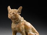 une photo représentant une statue de chien assis sur un bloc de bois