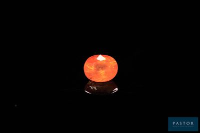 a close up of an orange stone on a black surface