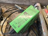 a green power supply sitting on the floor next to a pile of tools