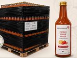une bouteille de sauce tomate à côté d'une caisse de tomates