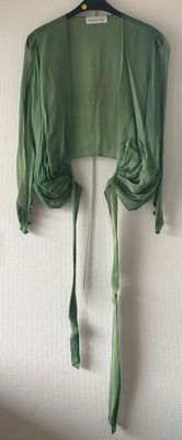 a green shirt hanging on a wall next to a hanger