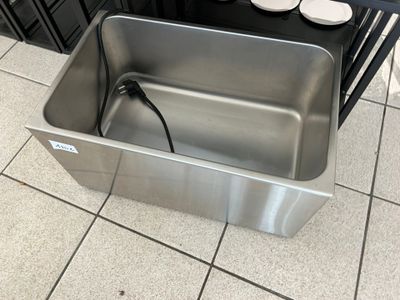 a stainless steel sink in the middle of a tiled floor