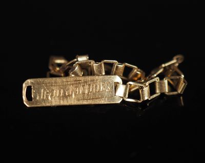 gros plan d'un bracelet en or sur une surface noire