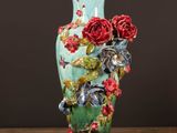 un vase vert orné de fleurs rouges, posé sur une table