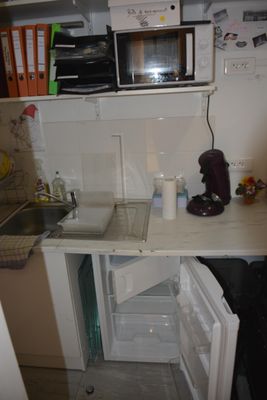 une photo d'une petite cuisine avec un réfrigérateur et un micro-ondes