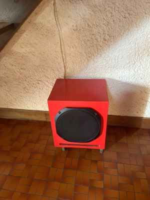 une enceinte rouge posée par terre devant un lit