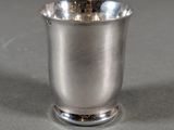 a silver cup sitting on a table on a gray surface