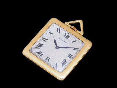 une petite horloge carrée dont le cadran est orné de chiffres romains