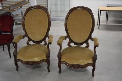 une paire de chaises anciennes dans une pièce, avec une table et des chaises en arrière-plan