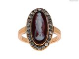 an image of a woman ' s ring with a red agate stone surrounded by black diamonds