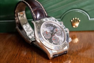 a watch sitting on a table with a green box in the background