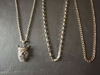 three necklaces on a black surface with a silver chain