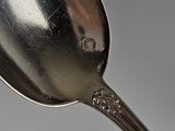 a silver spoon with a silver handle on a gray surface
